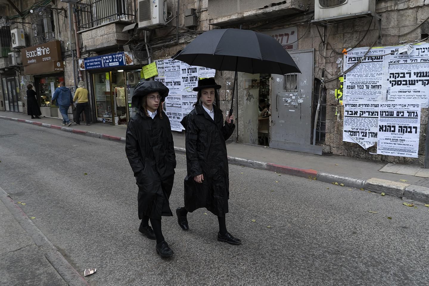 Dos jóvenes judíos se protegen de la lluvia en el barrio ultra ortodoxo de Mea Shearim en la ciudad de Jerusalén (Israel). | JOAQUÍN GÓMEZ SASTRE