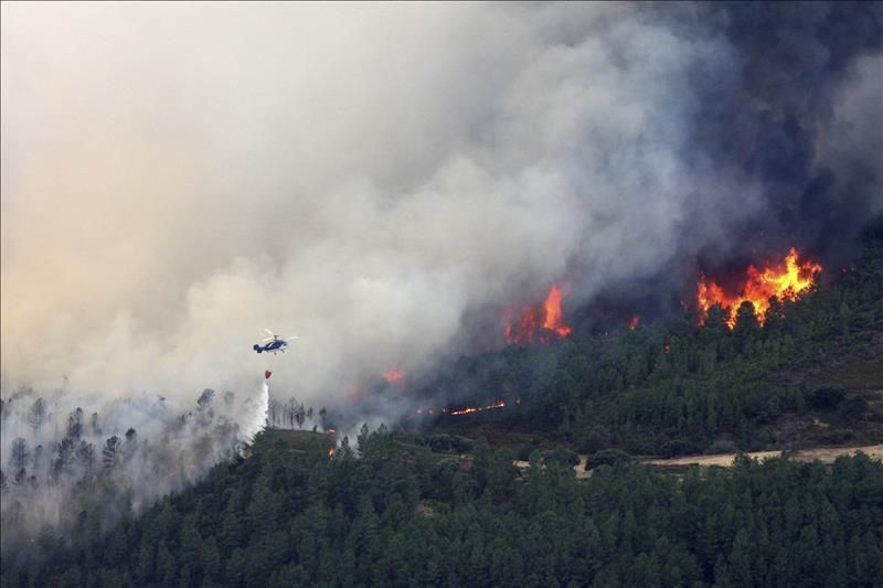 Vista de un helicóptero, realizando una descarga para controlar el incendio forestal declarado ayer en Acebo (Cáceres). El fuego ha quemado ya más de 5.000 hectáreas en Sierra de Gata. / EFE.