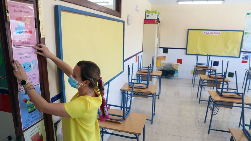 Archivo - Una profesora coloca carteles de medidas preventivas ante el COVID-19 en el aula antes del inicio del curso escolar. Archivo