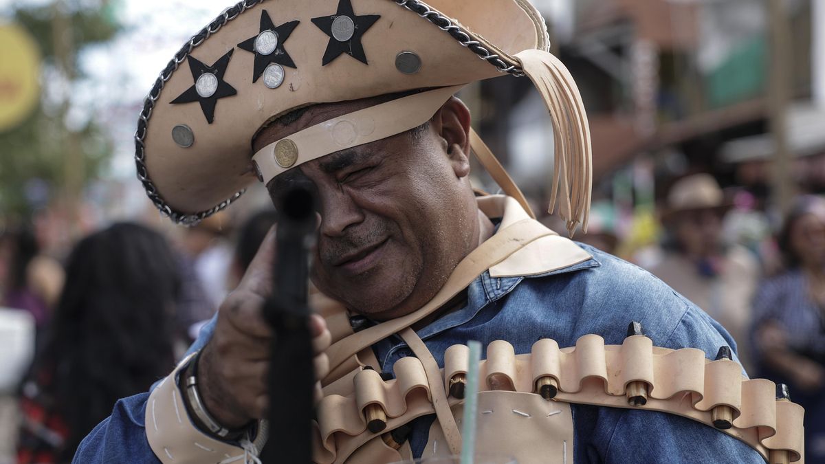 Un hombre con ropa típica de la historia de Pernambuco, apunta una arma falsa durante los festejos de la Fiesta de San Juan, el 10 de junio de 2023 en la región de la ciudad de Caruaru, interior del estado de Pernambuco, noreste de Brasil.. EFE/Antonio Lacerda