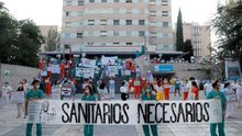 Miembros del personal sanitario del Hospital Gregorio Marañón posan con una pancarta en la que se lee "Sanitarios necesarios"