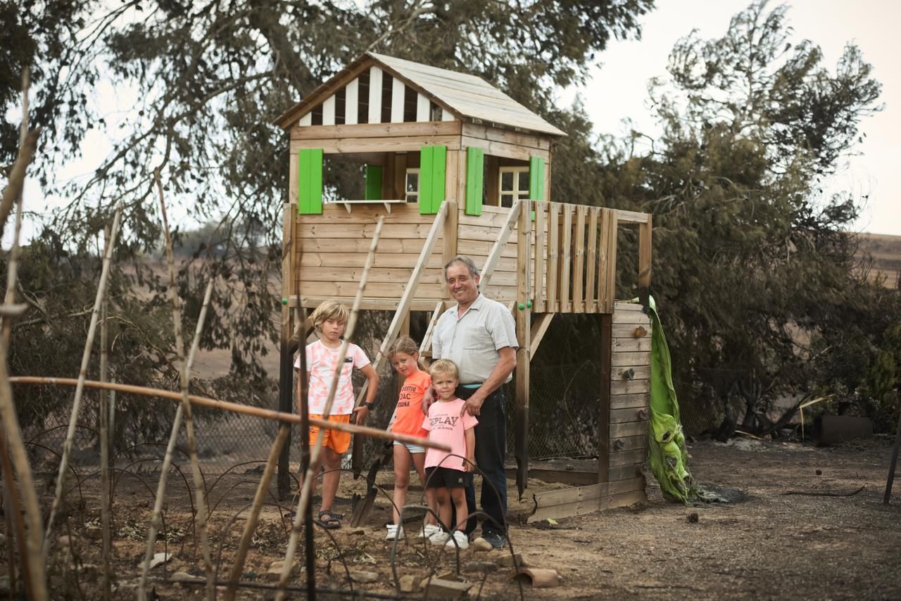 Pep Pampalona, agricultor de 65 años, junto a sus nietos en el patio alcanzado por el incendio