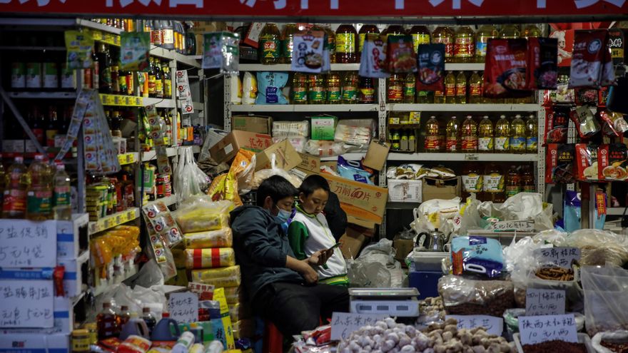 Un hombre junto a un niño en su puesto de un mercado en Pekín, China, el 20 de octubre de 2020. EFE/EPA/WU HONG