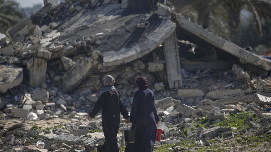 Mujeres palestinas desplazadas pasan junto a un edificio destruido en Deir Al Balah, en el sur de la Franja de Gaza, el 14 de febrero de 2024. EFE/EPA/MOHAMMED SABLE