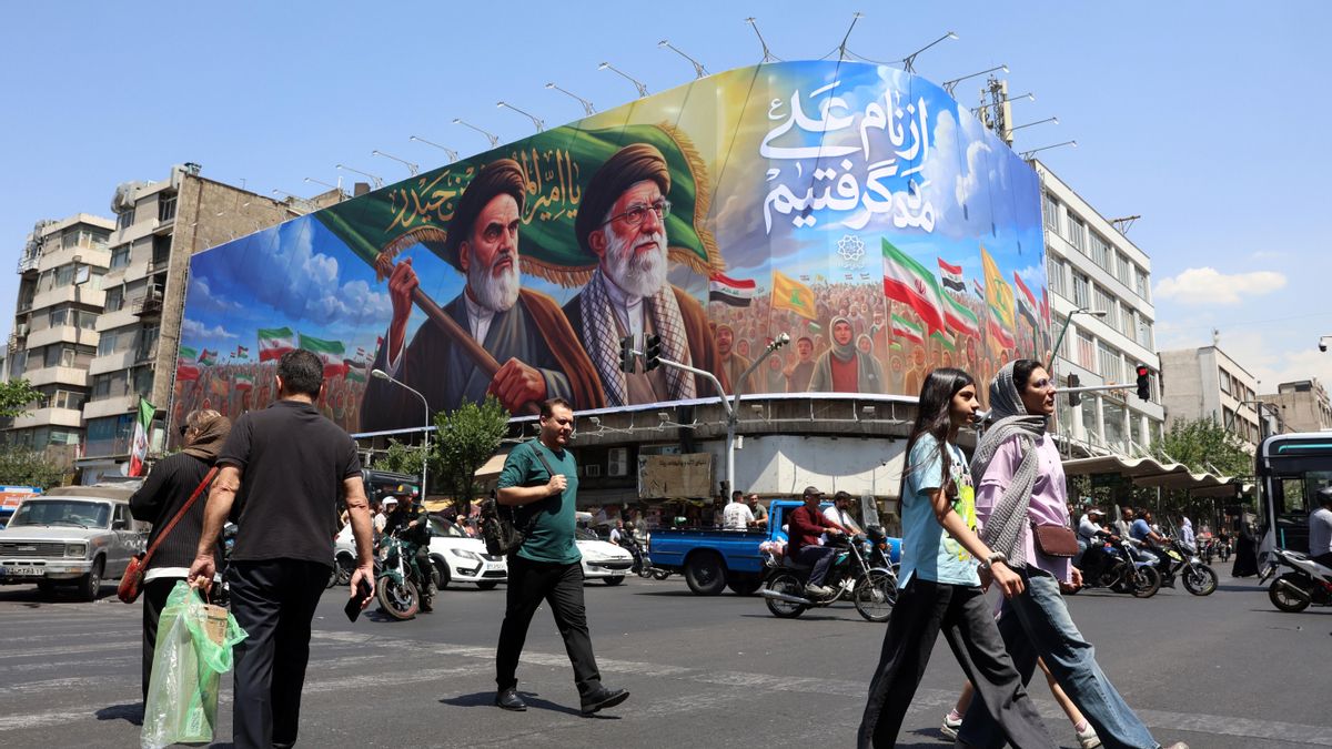 Ciudadanos iraníes pasan junto a una gran valla publicitaria con la imagen del difunto líder supremo iraní, el ayatolá Ruhollah Jomeini, y del líder supremo, el ayatolá Ali Jamenei, en una calle de Teherán.