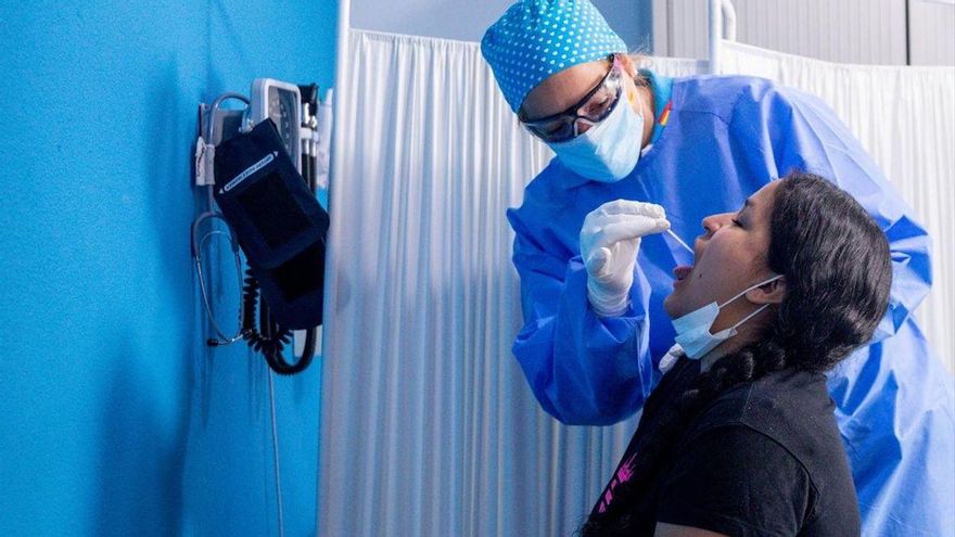 Un trabajador sanitario protegido le realiza a una mujer un test PCR, en una imagen de archivo