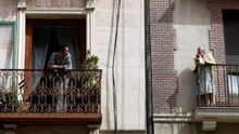 Una señora habla con su vecino desde el balcón en Madrid.