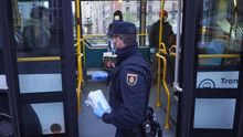 Un policía reparte mascarillas a los viajeros de un autobús en Pamplona.