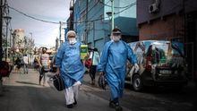 Personal sanitario con trajes de protección caminan cerca a un ingreso este viernes a la Villa 31 en la ciudad de Buenos Aires (Argentina).