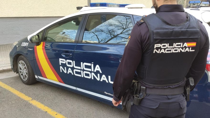 Archivo - Un agente de la Policía Nacional junto al coche policial.
