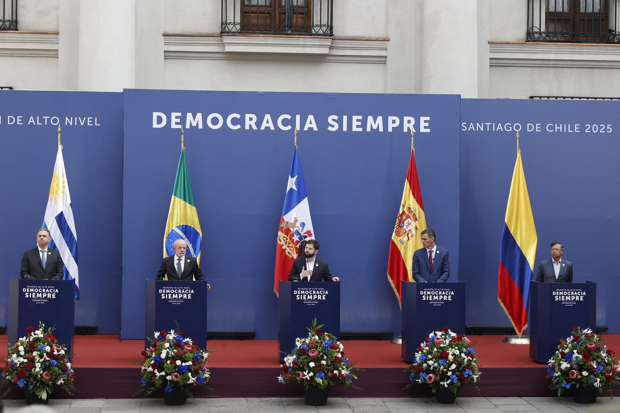 De izquierda a derecha: el presidente de Uruguay, Yamandú Orsi; el de Brasil, Luiz Inácio Lula da Silva; el de Chile, Gabriel Boric; el del Gobierno de España, Pedro Sánchez, y el de Colombia, Gustavo Petro, durante una declaración conjunta en el marco de la cumbre en defensa de la democracia, este lunes, en el Palacio de La Moneda, en Santiago (Chile).