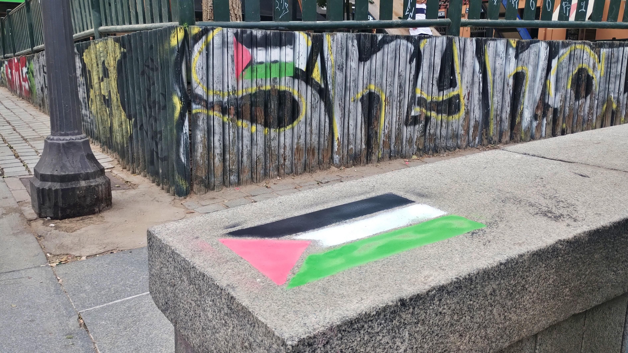 Varias banderas palestinas en lugares grafiteados de la plaza Dos de Mayo