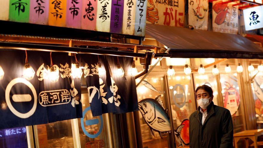 Un hombre con mascarilla camina por la calle en Tokio.