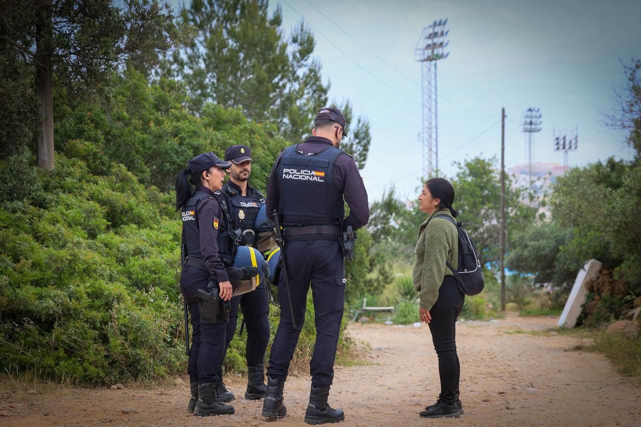 Una residente en el poblado chabolista habla con unos agentes de Policía Nacional