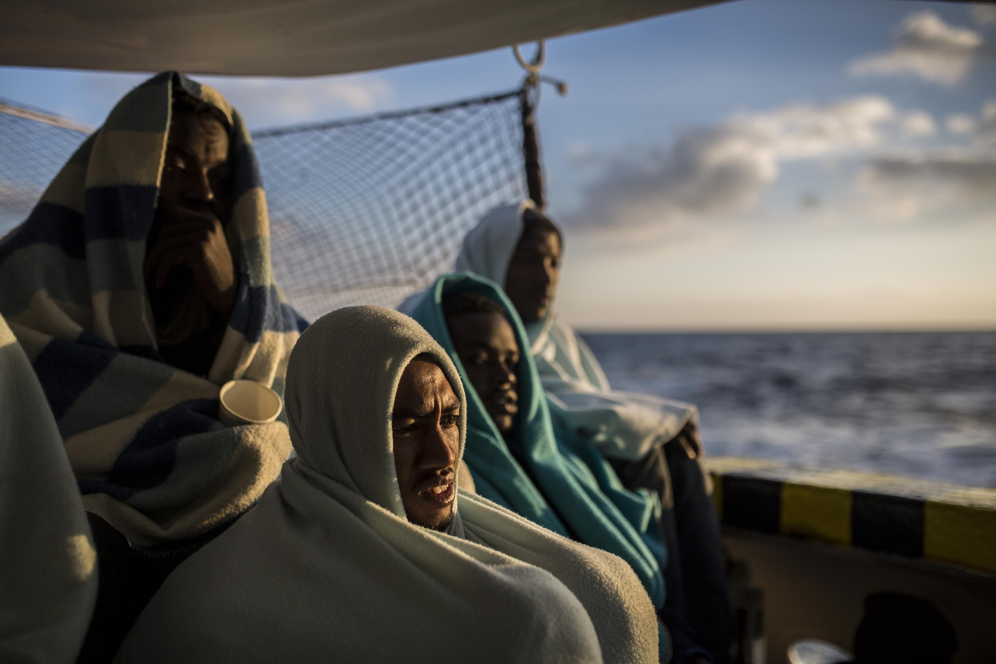 Algunas de las personas rescatadas por Proactiva Open Arms el pasado 21 de diciembre miran el mar desde la cubierta del barco de rescate / Olmo Calvo