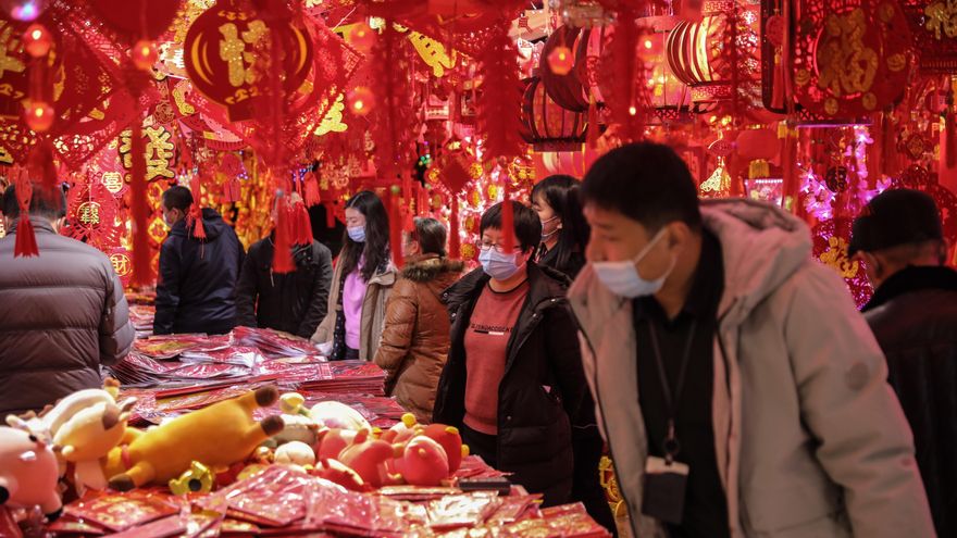 Ciudadanos chinos protegidos con mascarillas compran decoraciones de año nuevo para el próximo Año Nuevo Lunar Chino en un mercado en Pekín, China.EFE/EPA/WU HONG