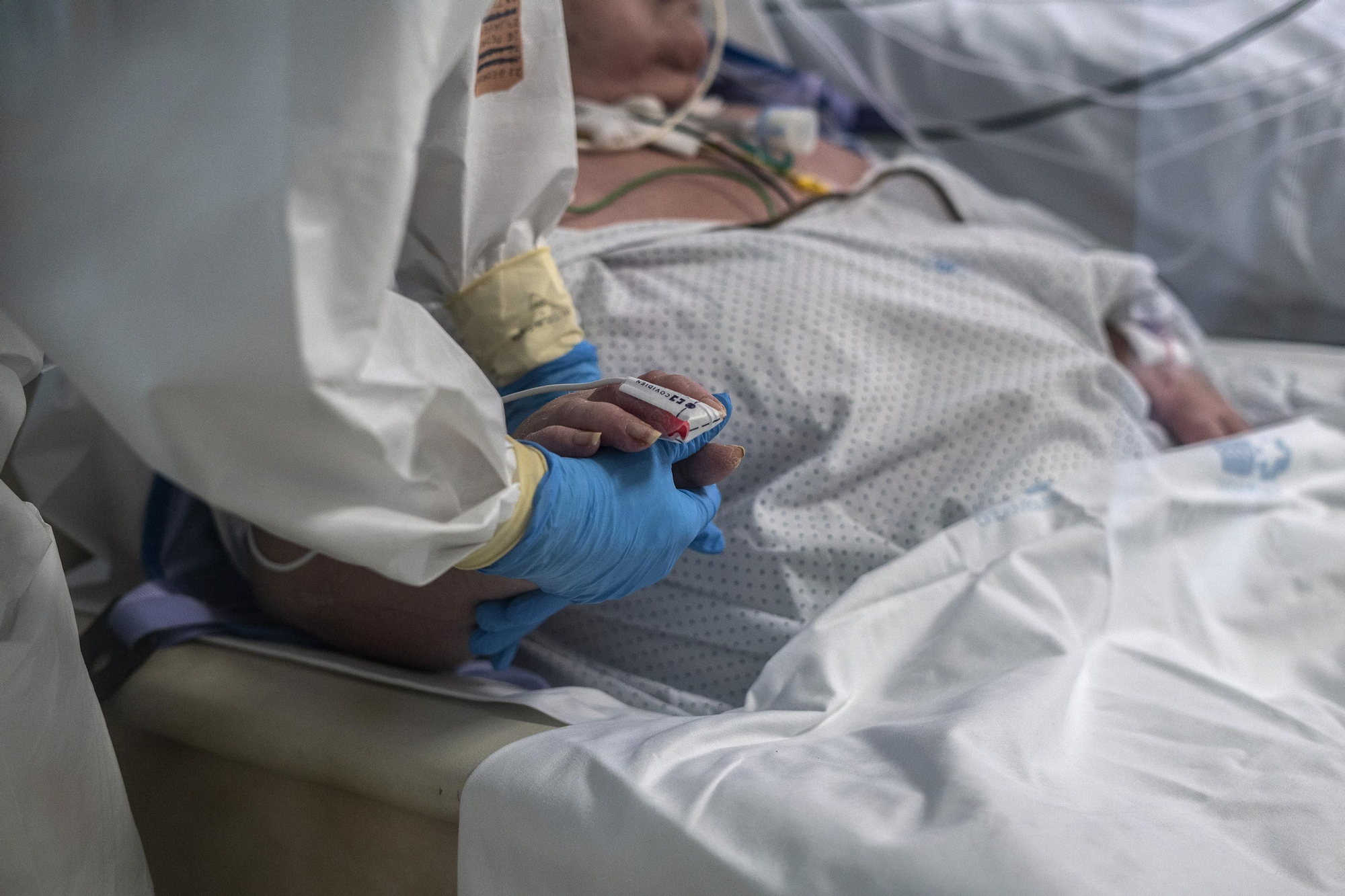 Una fisioterapeuta ejercita la mano de una mujer afectada por COVID-19.