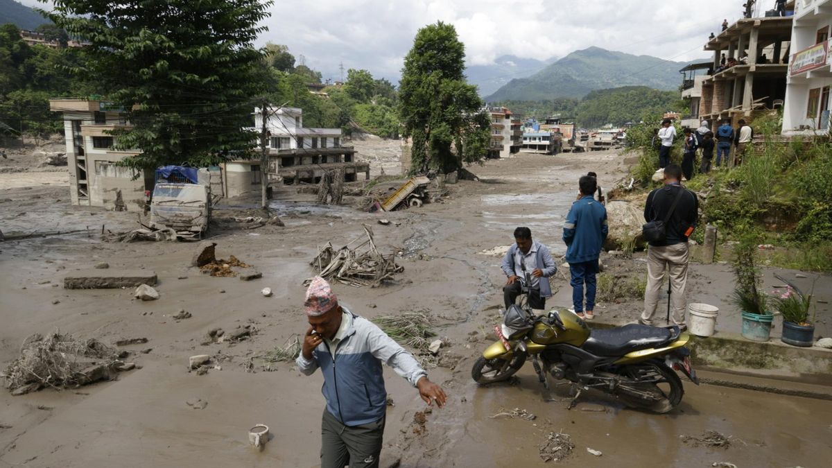 Varias personas caminan entre calles inundadas tras una crecida repentina en Trishuli Bazar.