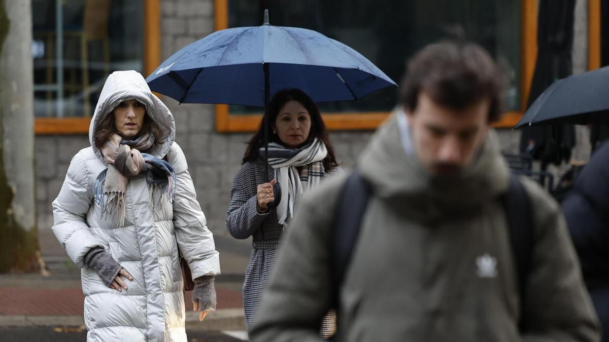 Varios transeúntes se protegen de la lluvia en Madrid.