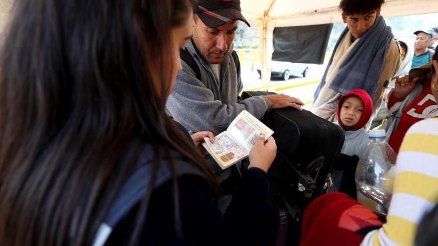 Una funcionaria revisa el pasaporte a un migrante venezolano en Rumichaca, en la frontera de Ecuador con Colombia.