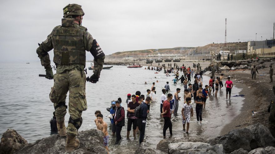 Un soldado español junto a los migrantes que han cruzado la frontera de Ceuta.
