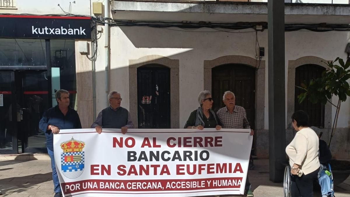 Vecinos muestran una pancarta de rechazo al cierre de la oficina de Kutxabank en Santa Eufemia.