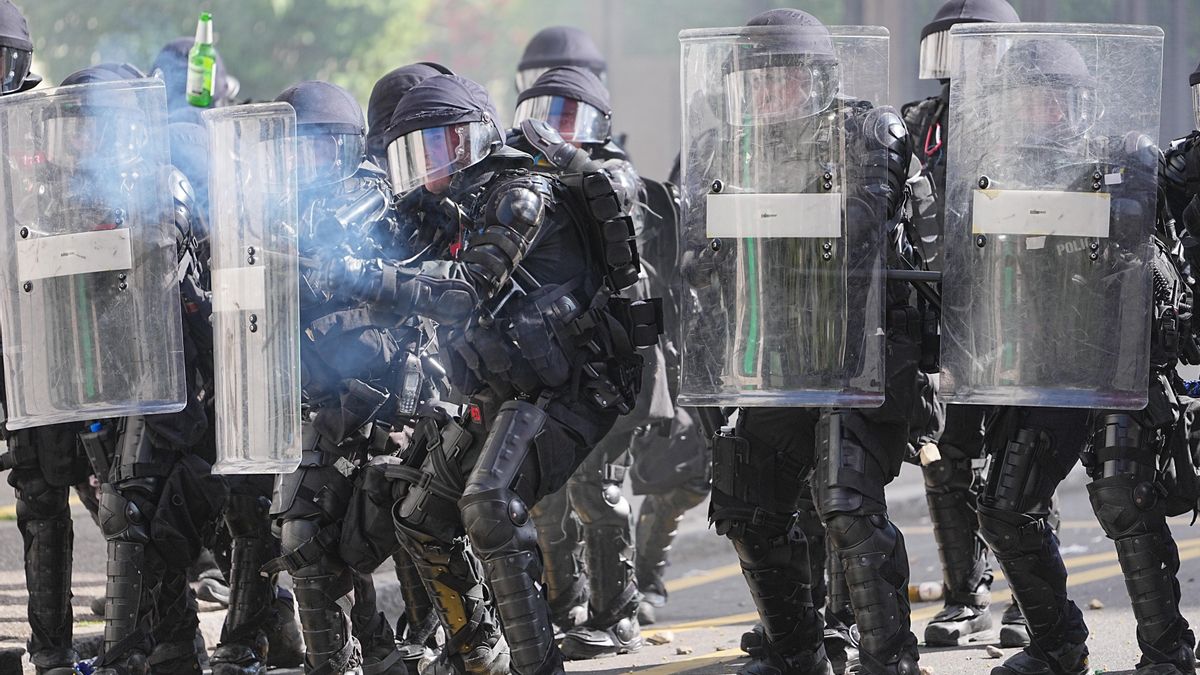 Policías suizos lanzan gases lacrimógenos y balas de goma a los manifestantes mientras reciben el impacto de una botella de cerveza este domingo en Ginebra.