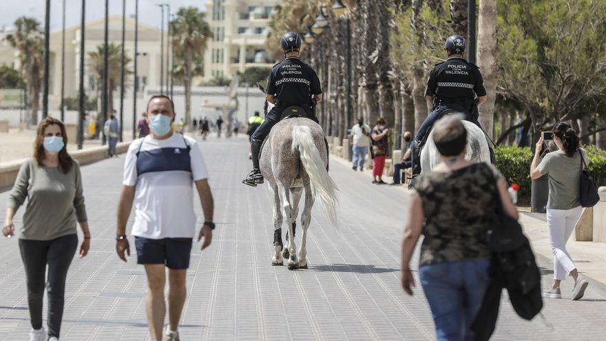 Archivo - Dos policías municipales patrullan a caballo por un paseo marítimo frente a una playa de València, a 26 de mayo de 2021