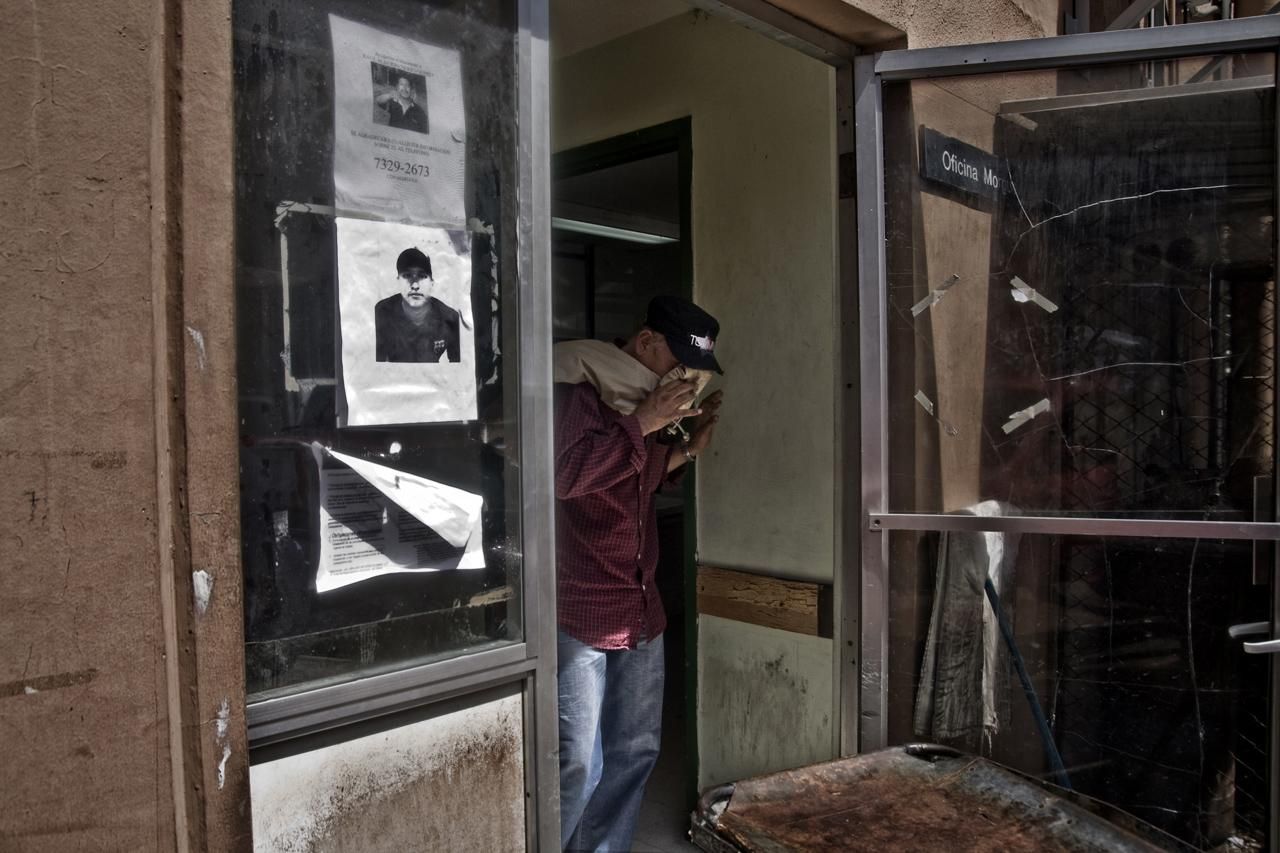 Un hombre llora en la puerta de la morgue del Hospital Rosales tras enterarse de que su hijo ha muerto. En las puertas de la morgue cuelgan carteles de gente desaparecida./Edu Ponces (RUIDO Photo)