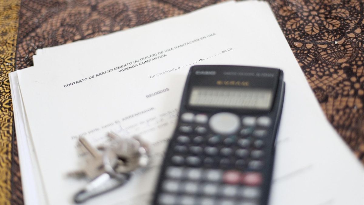 Una calculadora y unas llaves sobre un contrato de alquiler de una habitación en una vivienda compartida.
