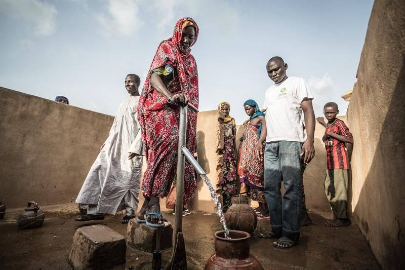 Akkoe Moussa, echando agua en un cántaro de cerámica junto a otras personas. FOTO: Pablo Tosco - Oxfam Intermón