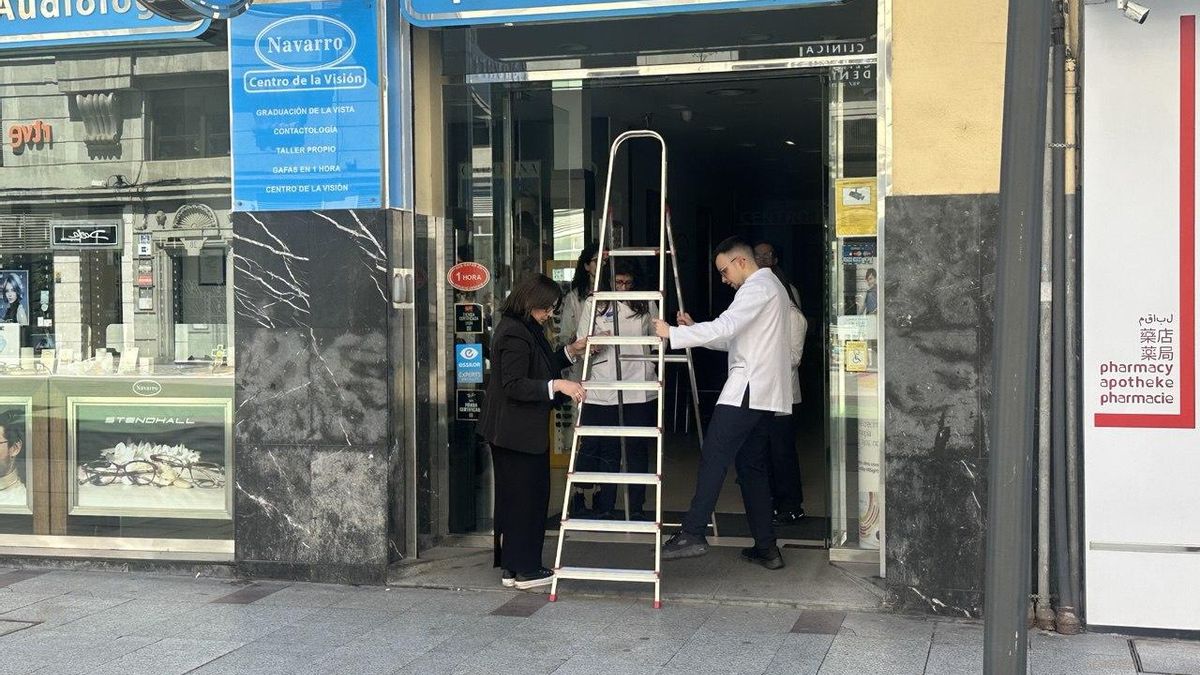 Dependientes intentando bajar la trapa para cerrar el negocio.