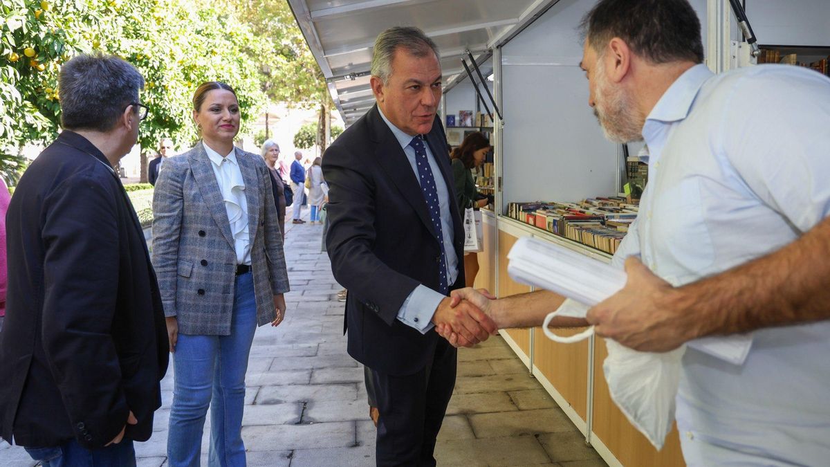 José Luis Sanz, acompañado por Minerva Salas, saluda a un librero en la Feria del Libro Antiguo.