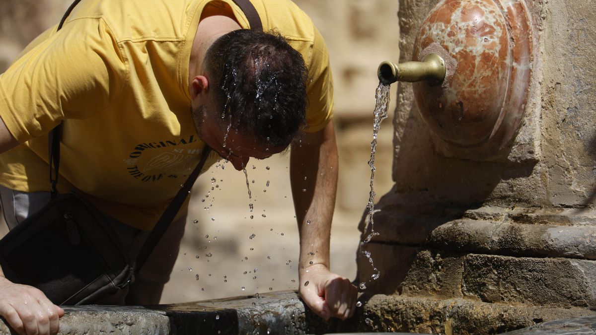 Imagen de archivo de un hombre refrescándose con agua de una fuente