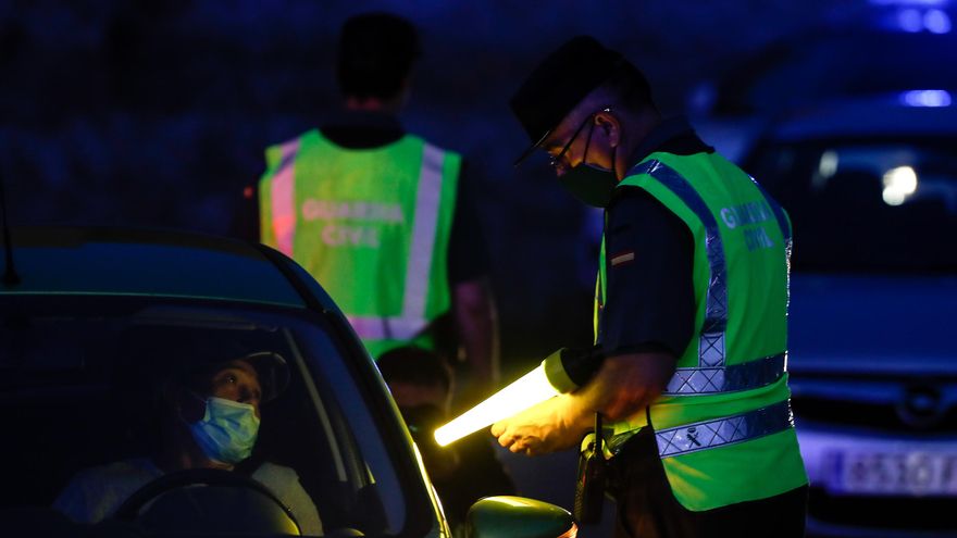 Un agente de la Guardia Civil pide la documentación a un conductor tras la entrada en vigor del estado de alarma en Madrid