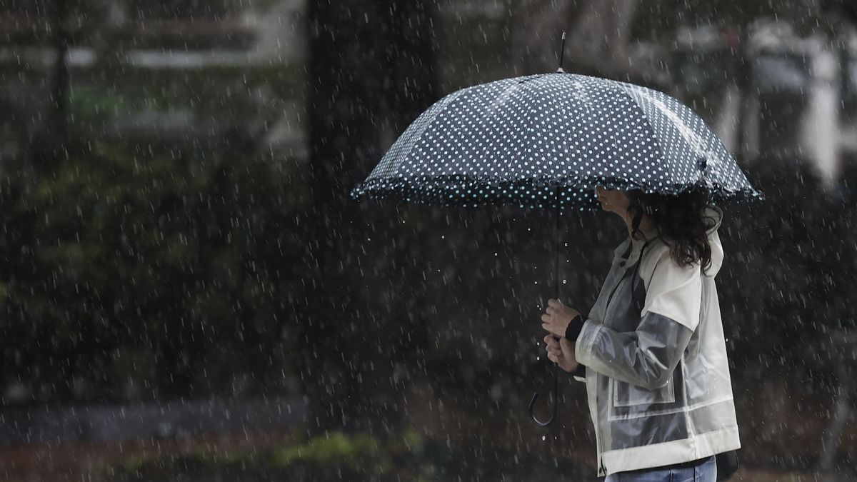 Imagen de archivo de una mujer que se protege de la lluvia con un paraguas.