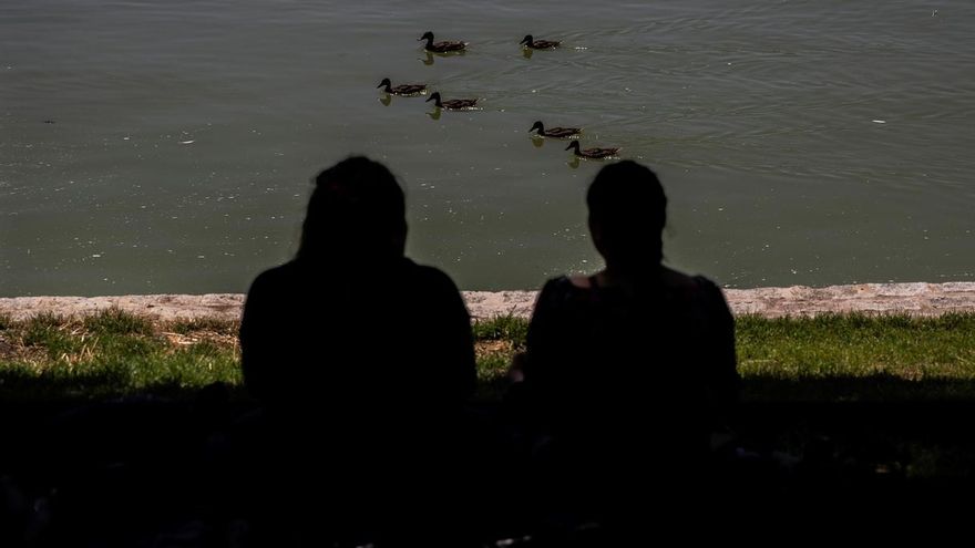 Dos personas toman el sol en el lago de la Casa de Campo en Madrid este martes.