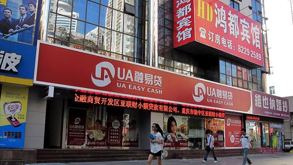 Varias personas caminan cerca de una sucursal del Banco central chino en la ciudad de Shenzhen. EFE