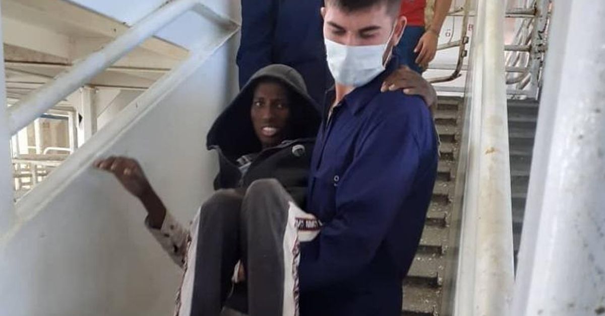 Un miembro de la tripulación traslada a una de las personas rescatadas que no puede caminar.