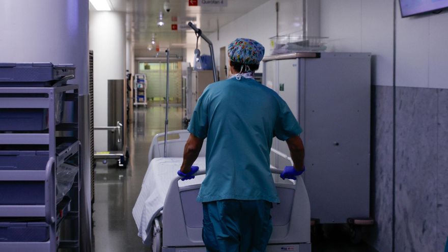 Archivo - Un celador transporta una camilla vacía en un pasillo que comunica los quirófanos de un hospital