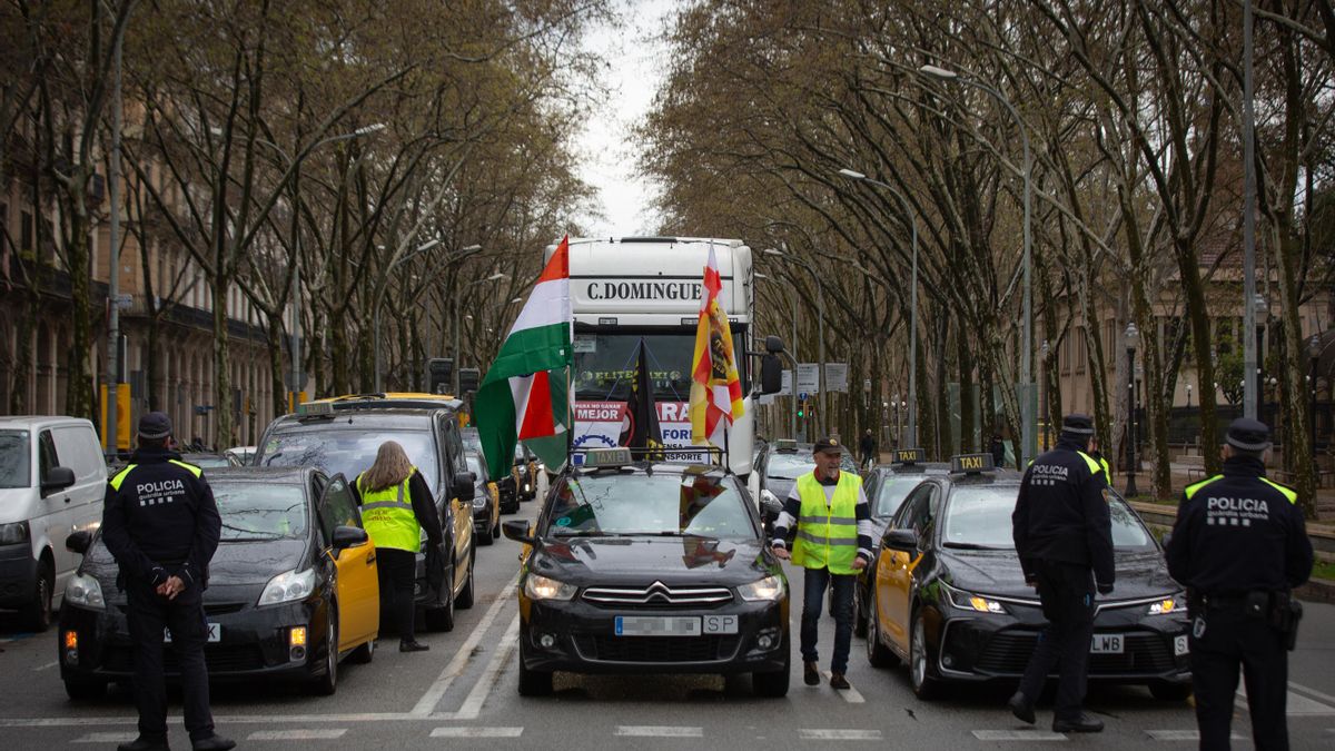 Varios taxistas y un camión, durante una marcha lenta de taxistas, desde la T1 del Aeropuerto de El Prat de Barcelona al Parlament, a 23 de marzo de 2022, en Barcelona.