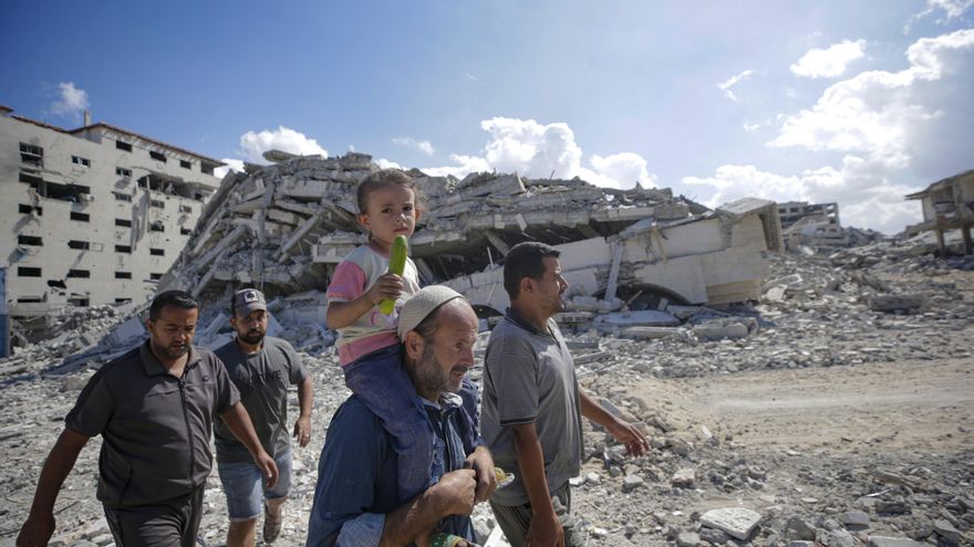 Palestinos caminan por una calle de Ciudad de Gaza entre los escombros de edificios destruidos.