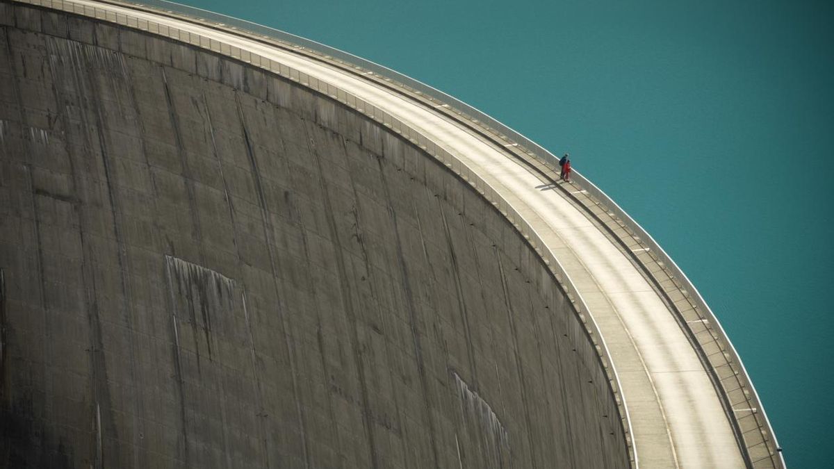 Dos personas observan el borde de una presa