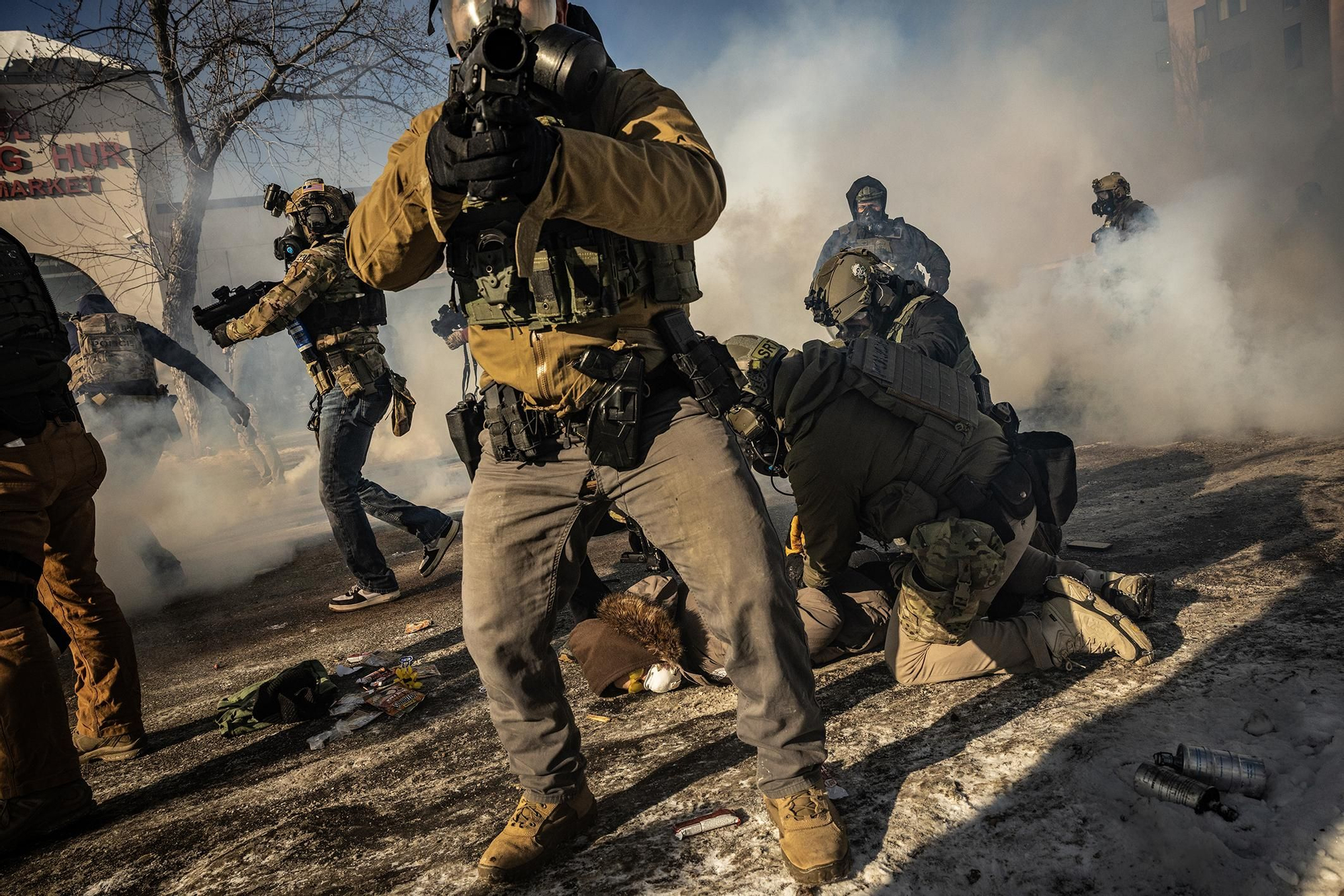 Agentes federales armados detienen a un manifestante en una calle de Minneapolis cubierta por una nube de gases lacrimógenos, después de que Alex Pretti fuera tiroteado y muerto por agentes. 24 de enero de 2026. © David Guttenfelder / The New York Times.