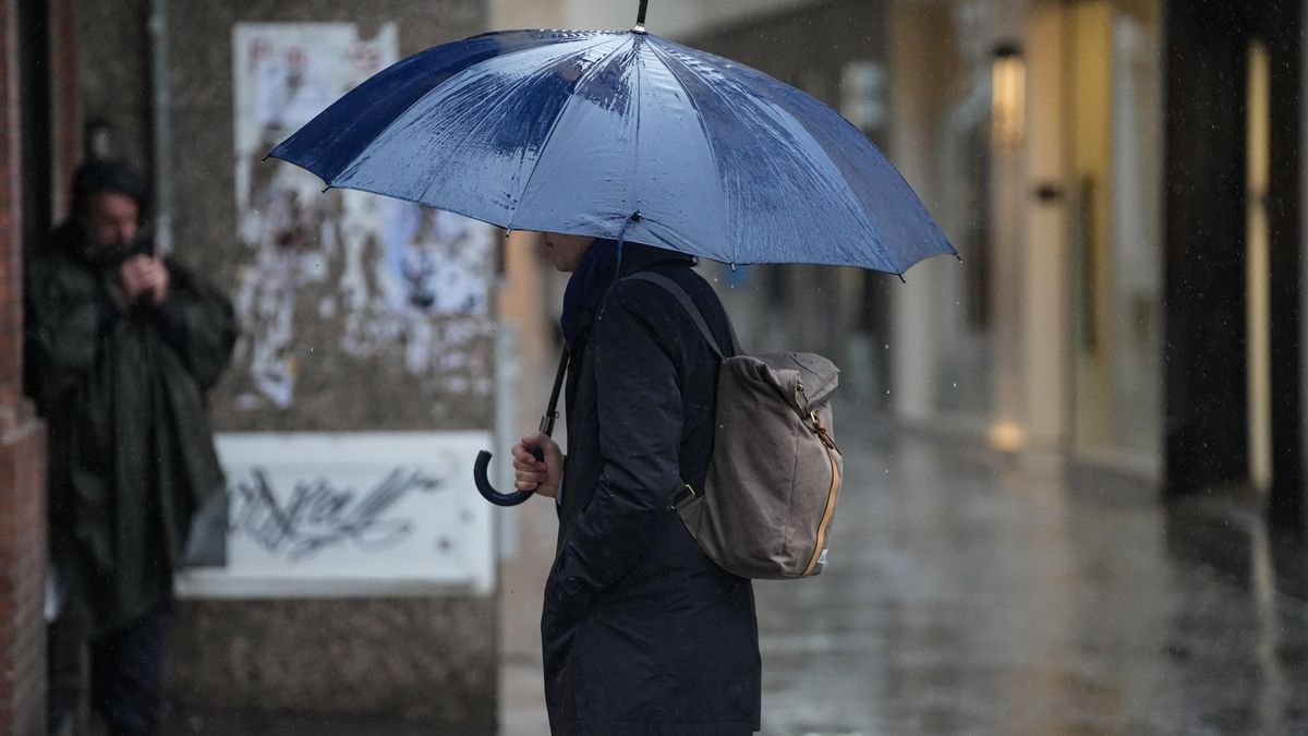 Transeúnte por una céntrica calle de Sevilla bajo la lluvia.