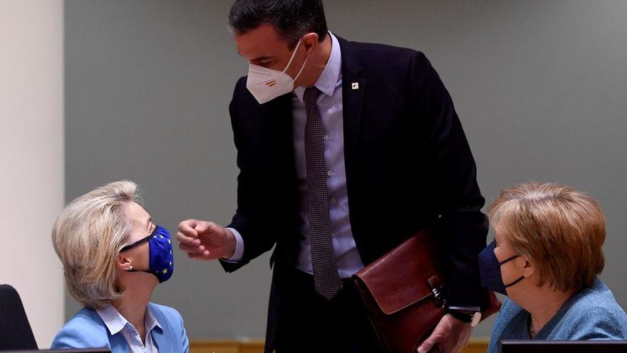 La presidenta de la Comisión Europea, Ursula von der Leyen recibe un regalo del presidente del Gobierno español, Pedro Sanchez, en presencia de la canciller alemana, Angela Merkel, en Bruselas.