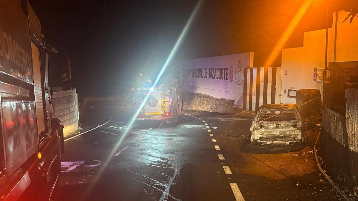 Dos camiones de Bomberos La Palma junto al coche incendiado en Tazacorte en la madrugada de este viernes.