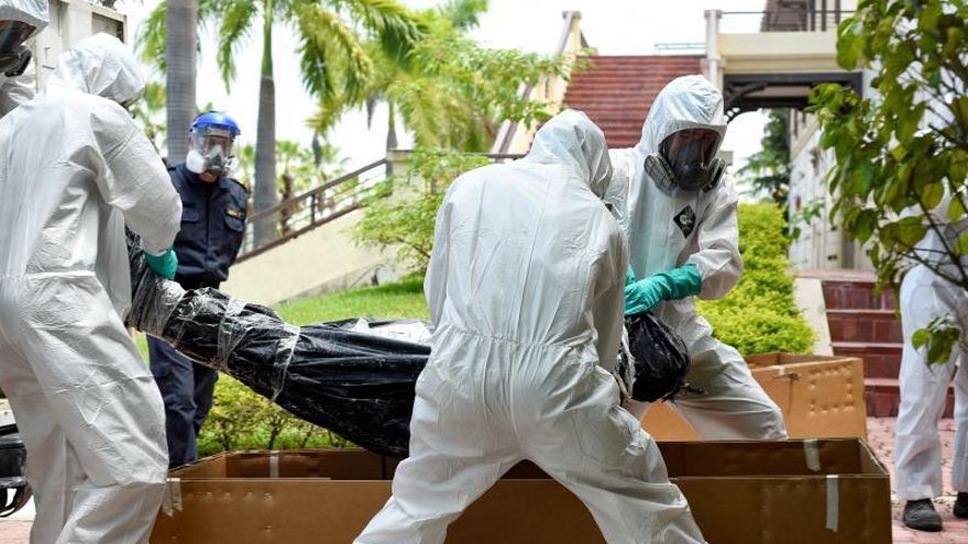 Trabajadores del cementerio Parques de la Paz cargan a un fallecido presuntamente por COVID-19 este lunes en sector de la Aurora de Daule, provincia de Guayas (Ecuador).