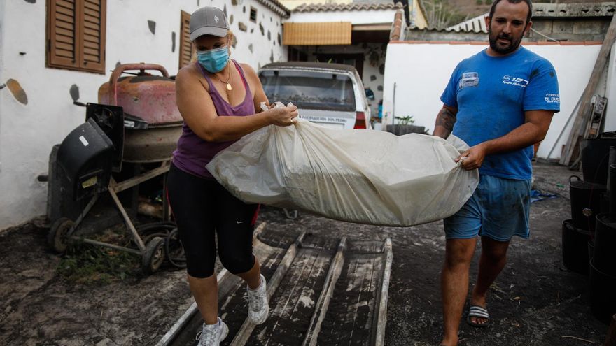 Un hombre y una mujer sacan sus pertenencias de su casa por la actividad del volcán en La Palma.