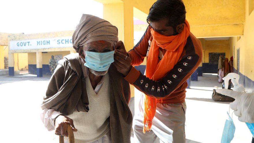 Jammu (India), 28/11/2020.- An Indian man ties protection mask on the face of an elderly man at a polling station during the first phase of the District Development EFE/EPA/JAIPAL SINGH